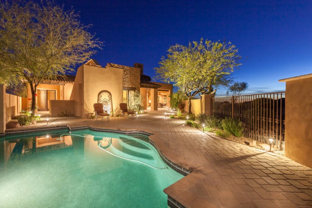 Landscape lighting illuminating a walkway and trees in a Phoenix backyard at dusk